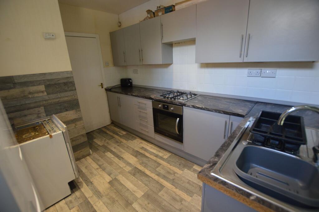 A modern kitchen featuring grey cabinetry with ...