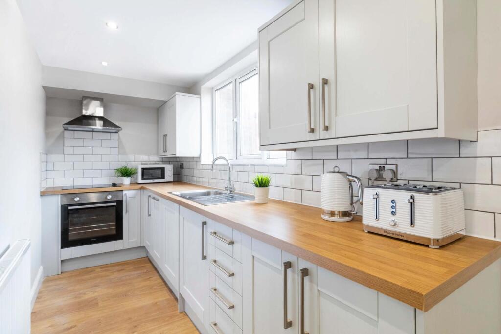 Bright, modern galley kitchen with white cabine...