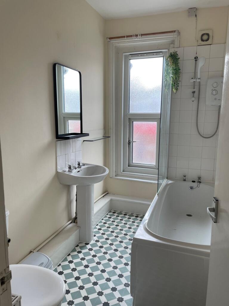 Bright and clean bathroom featuring a bathtub, ...