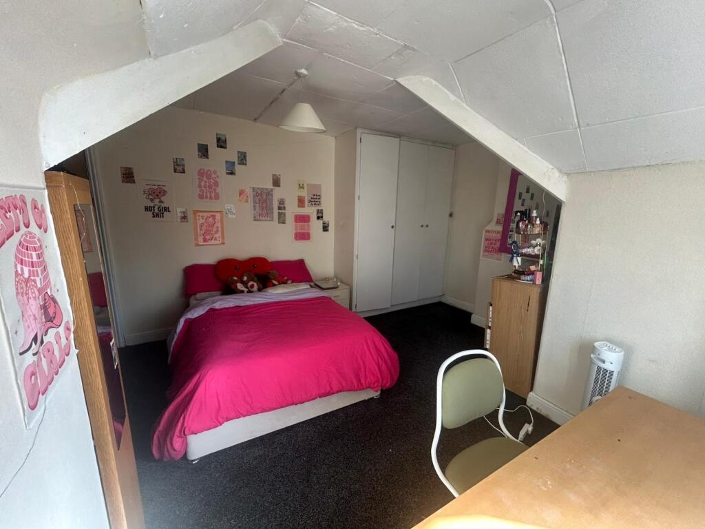 A well-lit double bedroom featuring a cozy bed ...