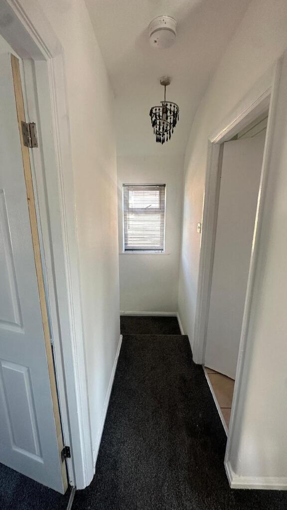 A narrow, well-maintained hallway with white wa...