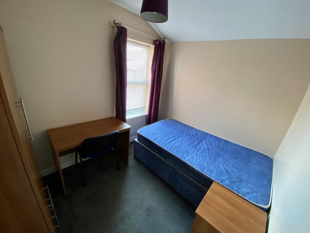 A bright and tidy single bedroom featuring a de...