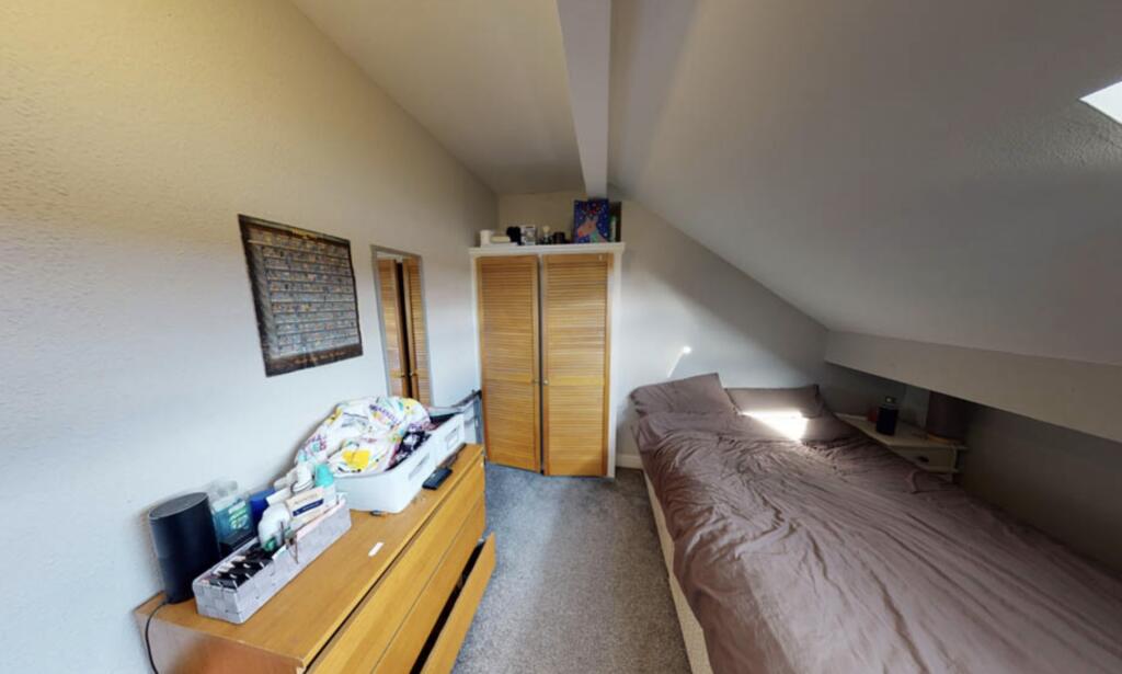 A cozy single bedroom featuring a neatly made b...