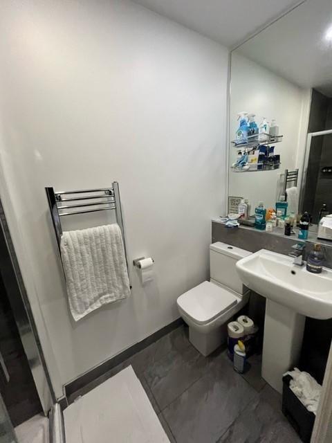 Modern bathroom with a pedestal sink, toilet, l...
