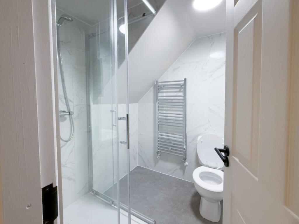 Modern white bathroom with a glass-enclosed wal...