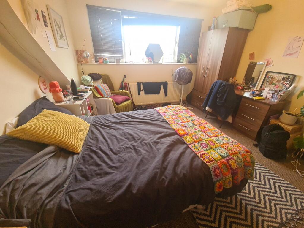 A cozy bedroom with a double bed covered in dar...
