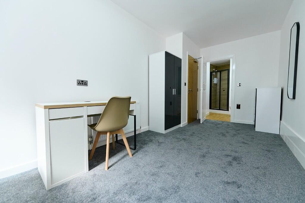 A clean, bright single bedroom featuring a mode...