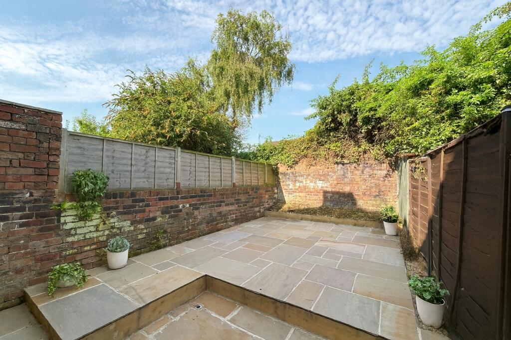 A charming private garden with a clean, paved p...