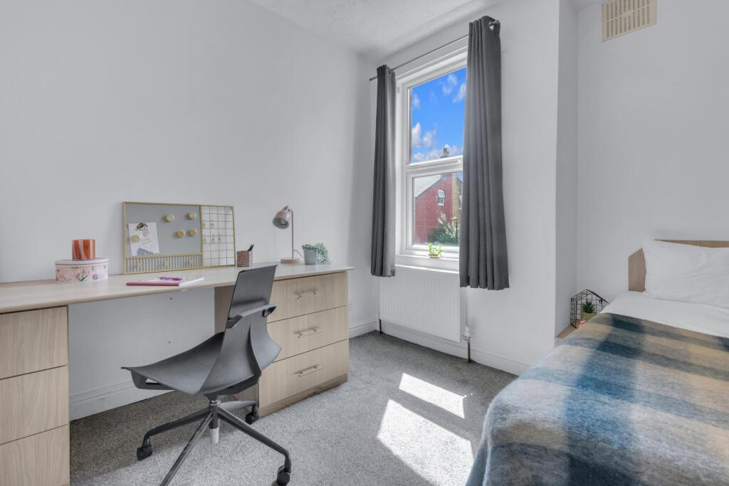 A bright and tidy single bedroom featuring a co...