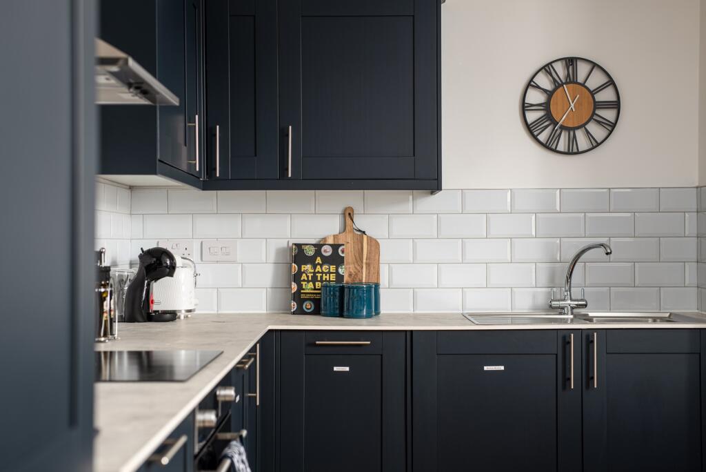 This modern kitchen features sleek navy cabinet...