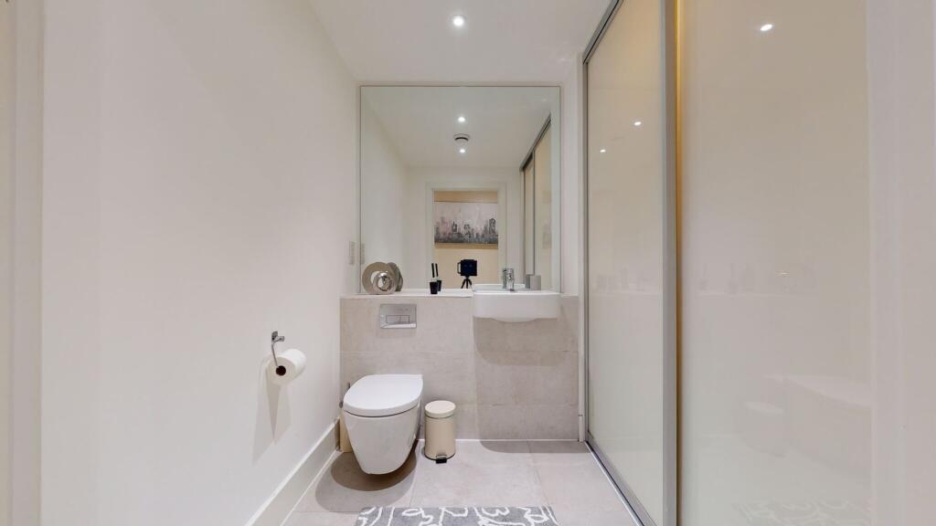 A modern and pristine single toilet space featu...