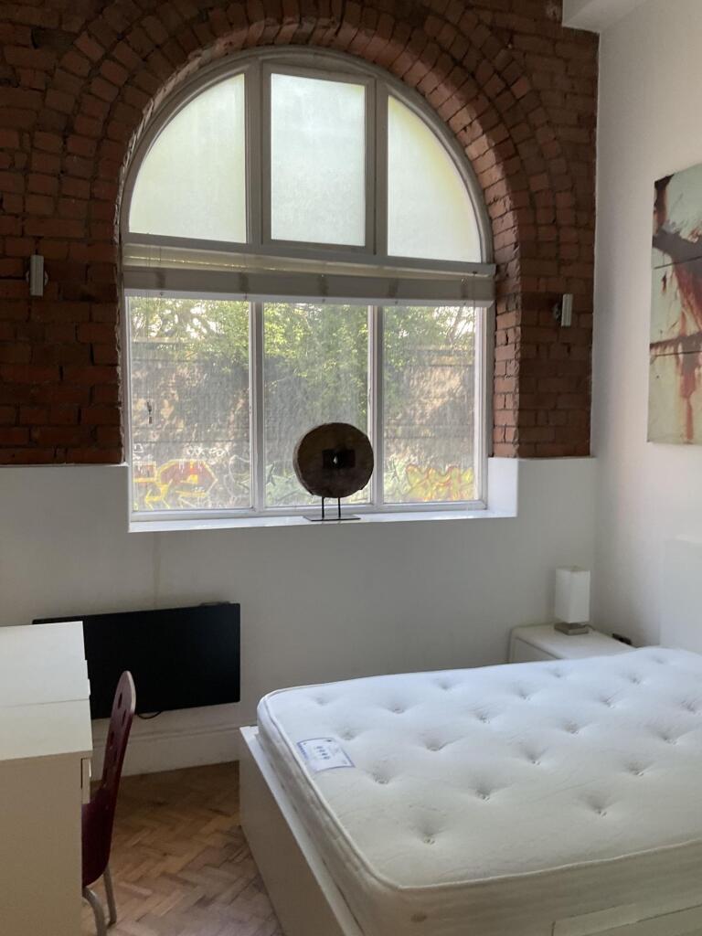 Bright double bedroom featuring a large arched ...