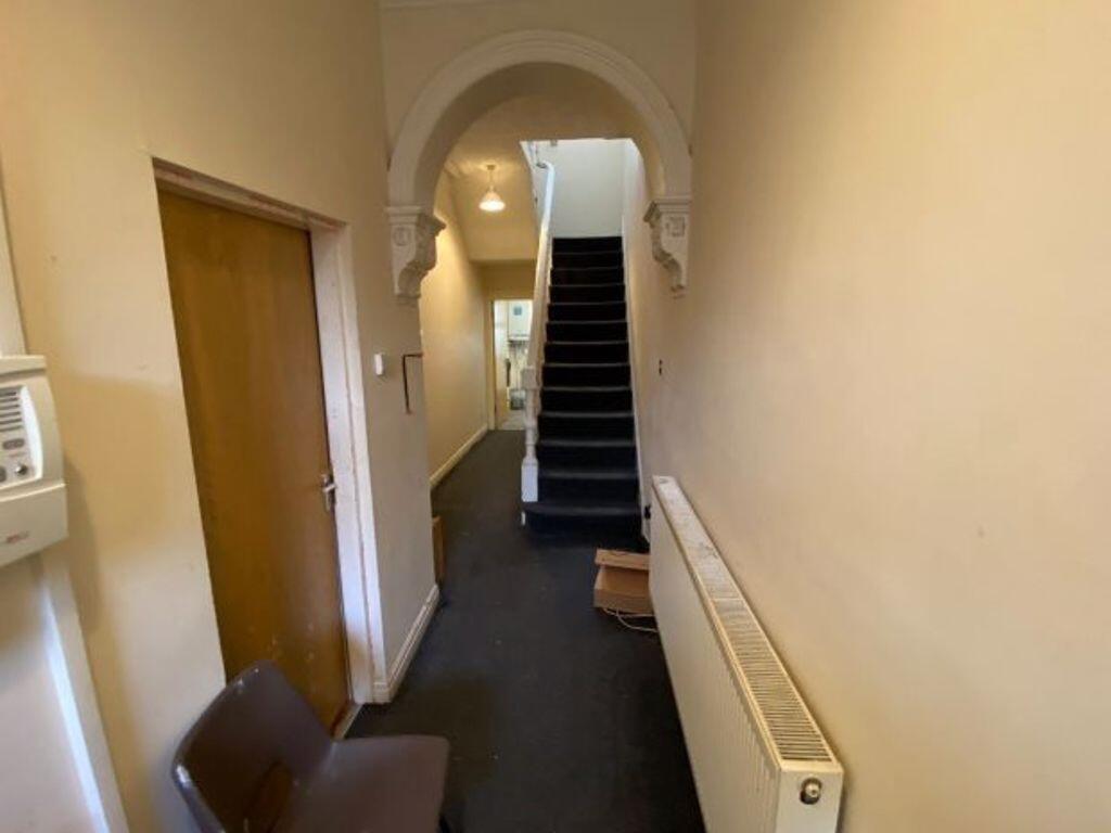 A clean, narrow hallway with neutral walls and ...