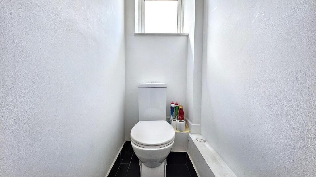 A clean and bright single toilet with white wal...