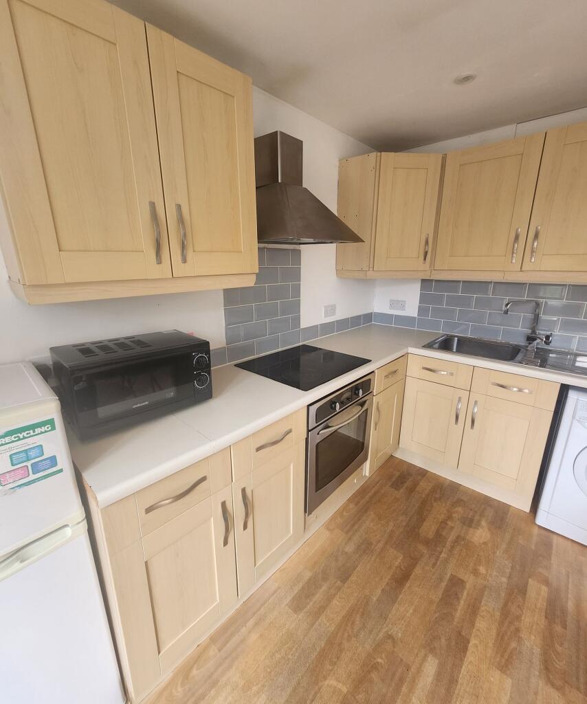 Bright and tidy kitchen featuring light wood ca...