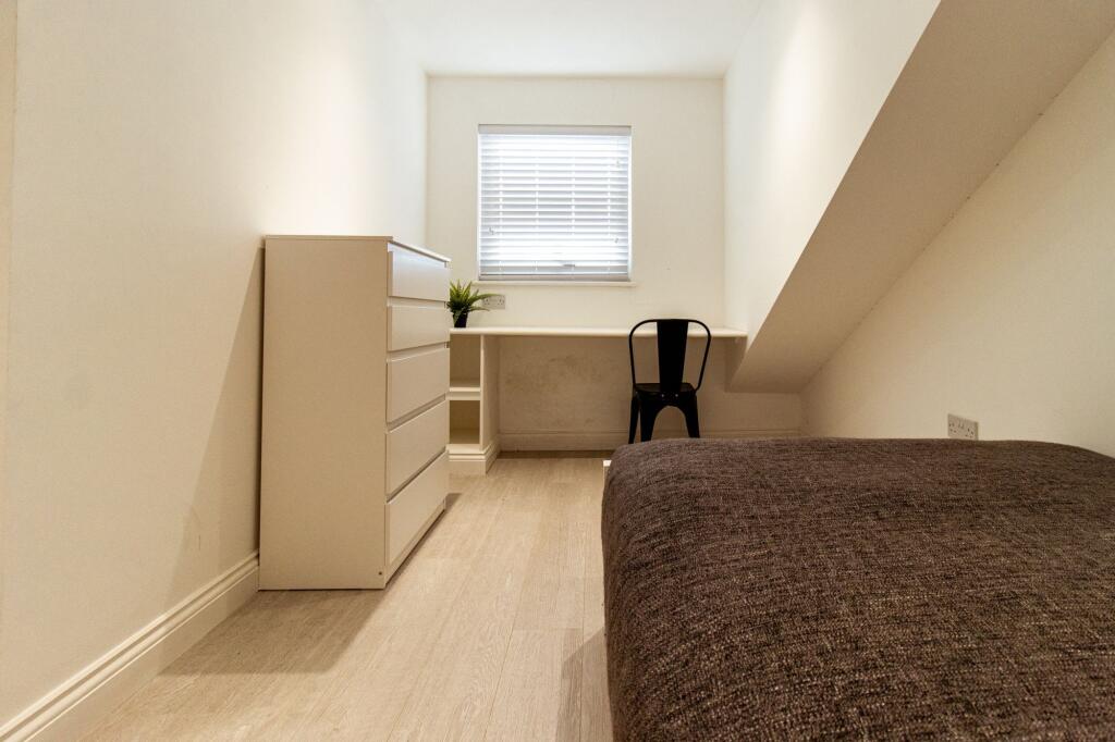 Simple, tidy single bedroom with a built-in des...