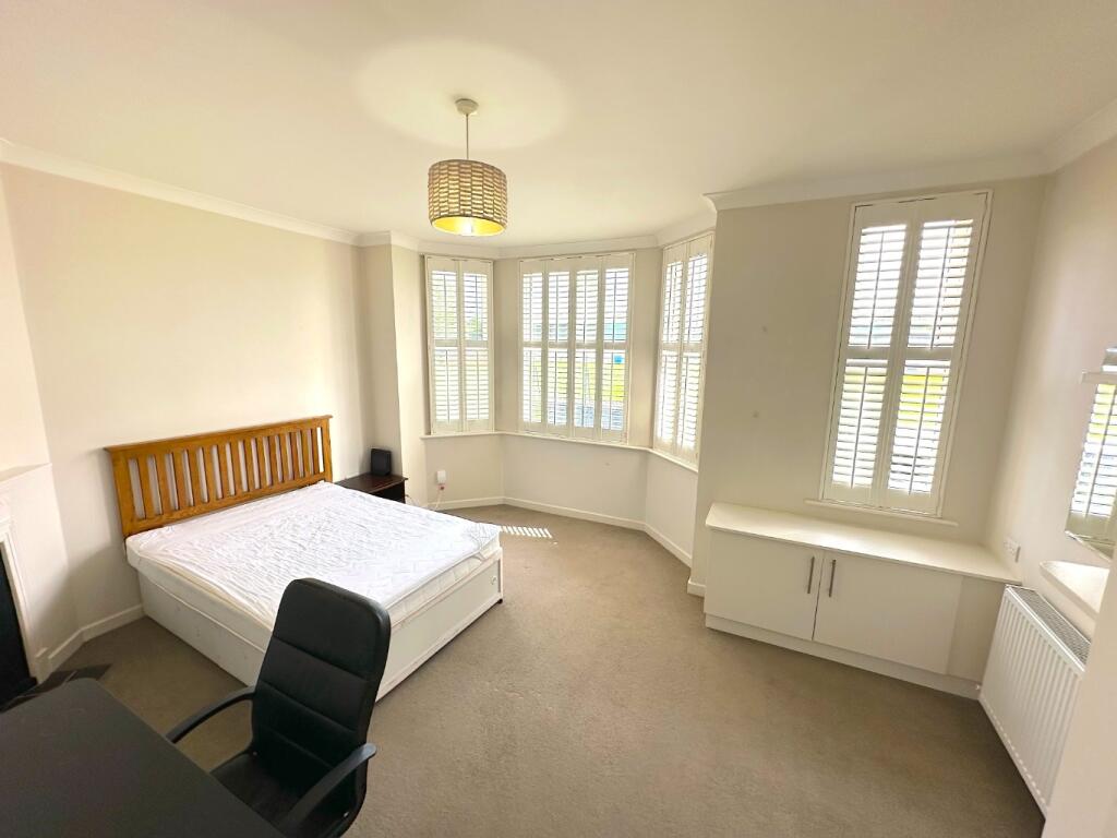 Bright double bedroom with a large bay window a...