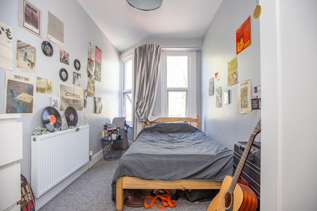 Cozy single bedroom featuring a wooden bed fram...