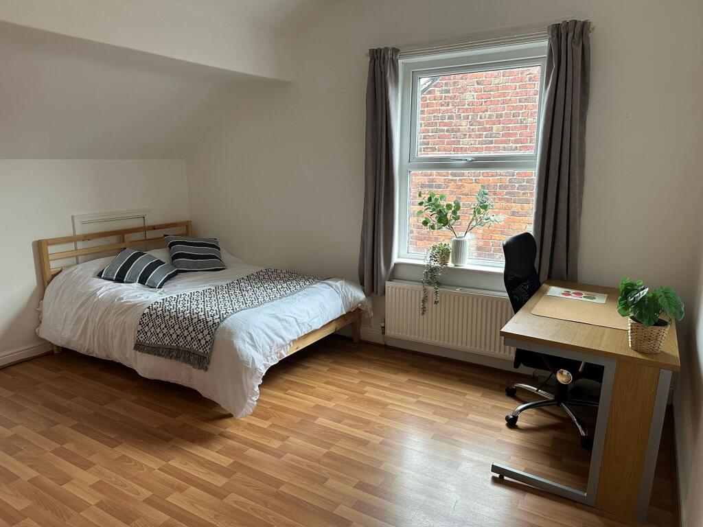 A tidy and bright bedroom featuring a comfortab...