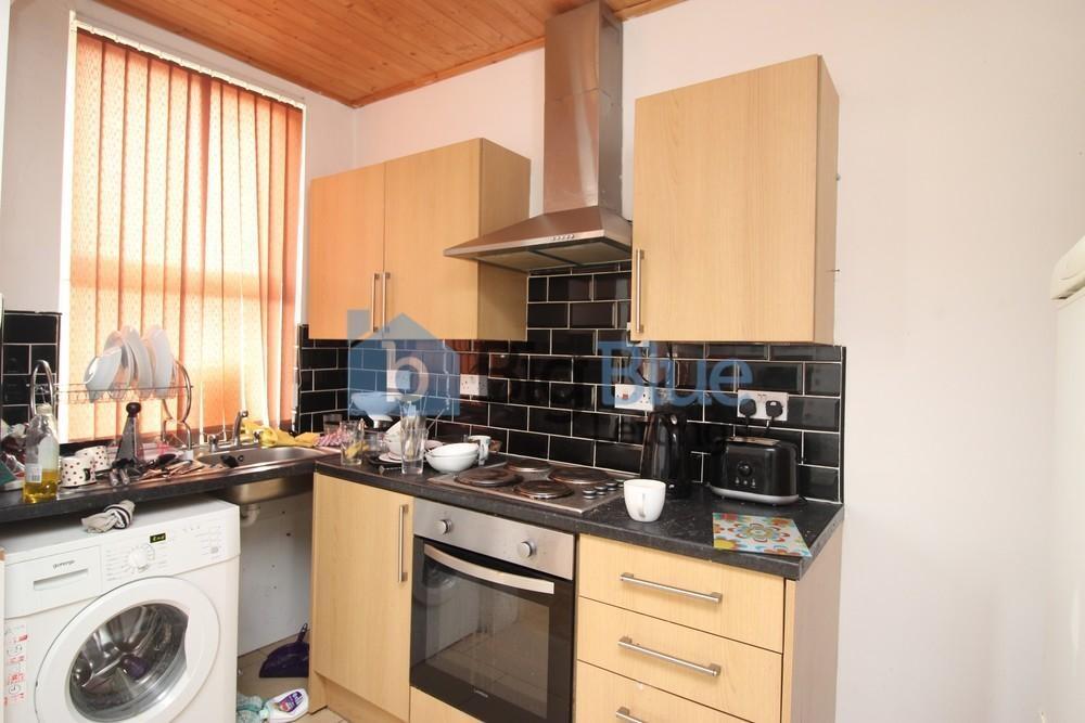 A compact kitchen featuring light wood cabinetr...