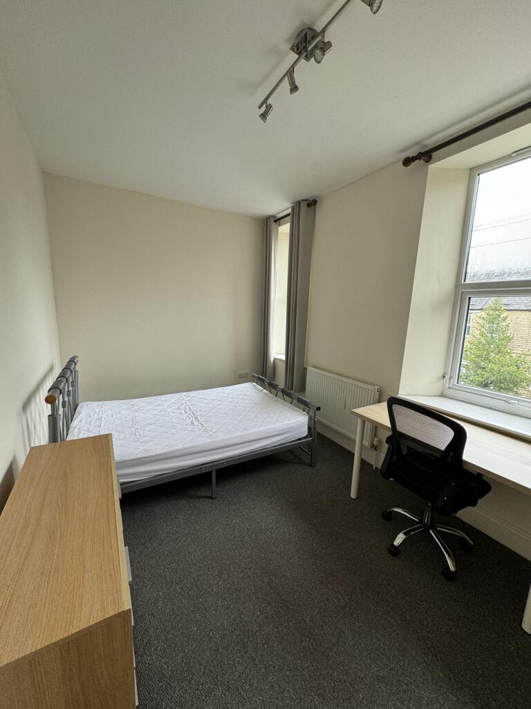 A clean and well-lit bedroom with a single bed,...