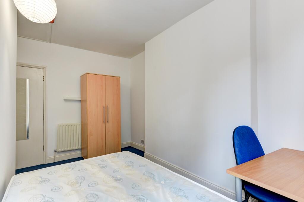 A tidy, bright single bedroom featuring a wardr...