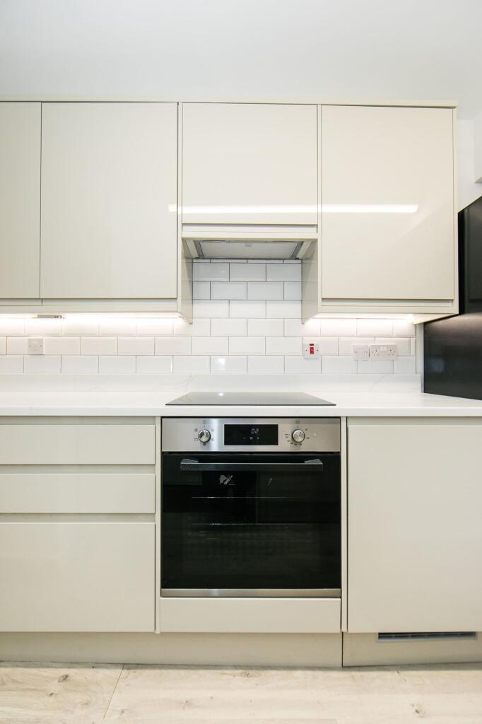 A modern, tidy kitchen featuring white cabinetr...