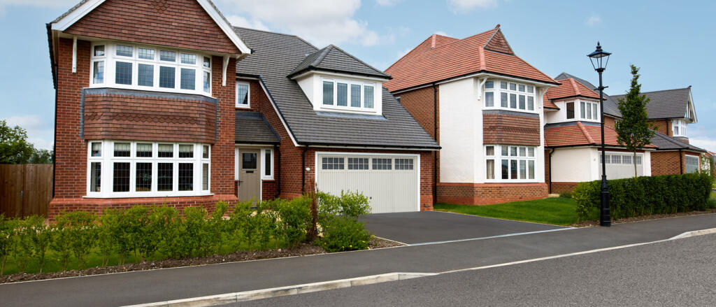 Modern detached houses with bay windows, red and white exteriors, and well-maintained front gardens