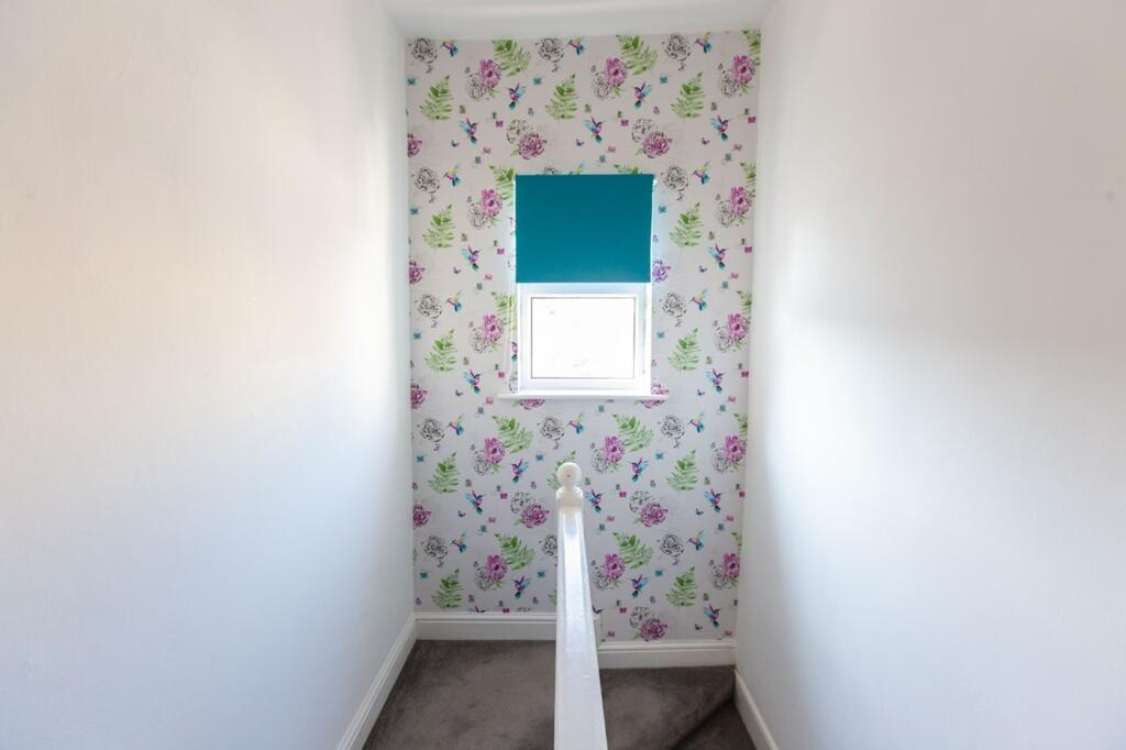 A clean but narrow hallway with floral wallpape...