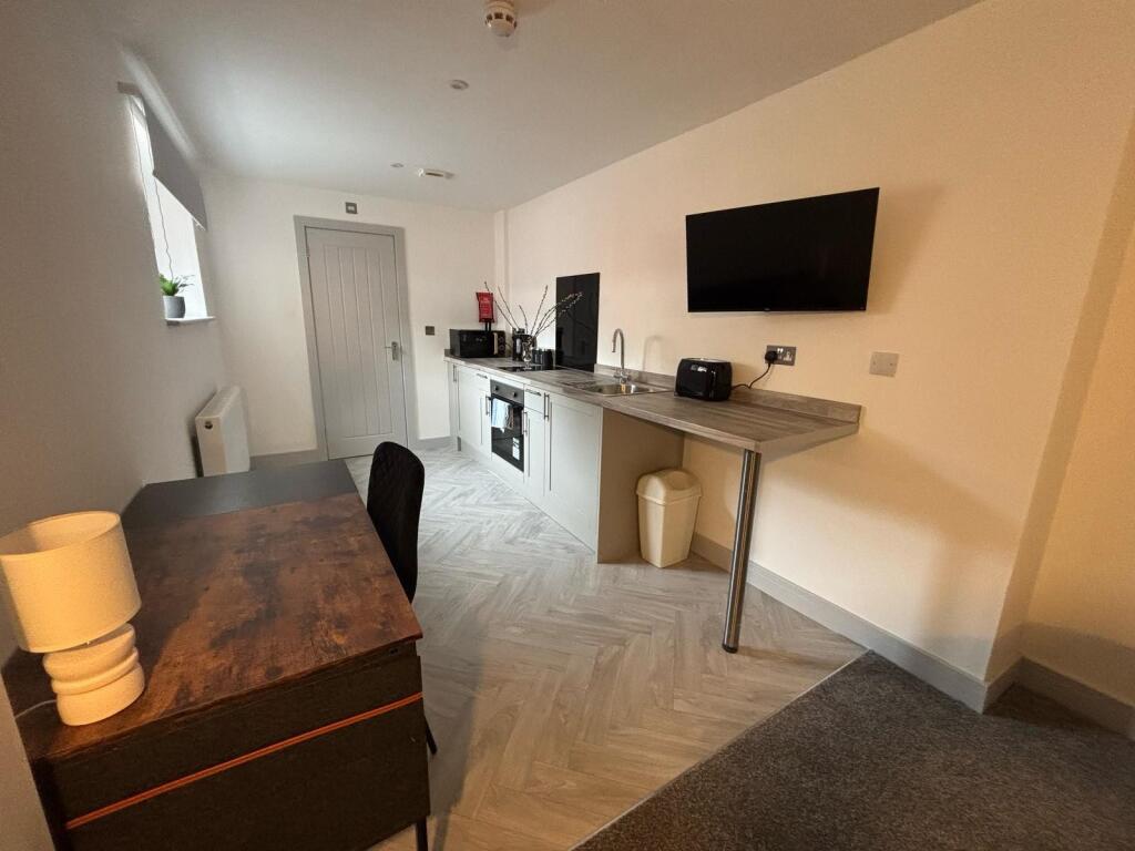 Modern kitchenette featuring sleek countertops,...