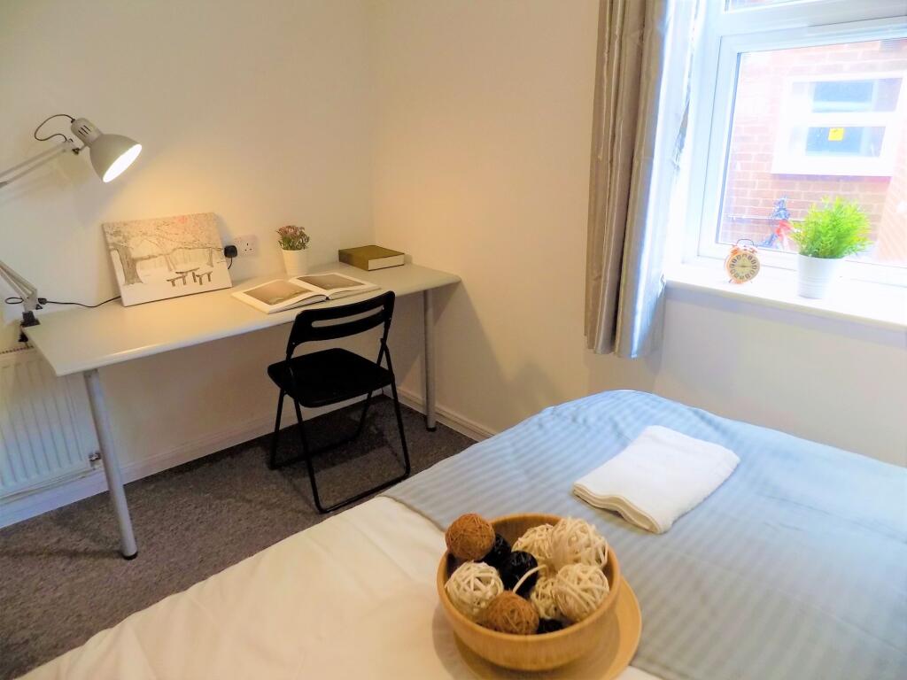 A cozy and tidy single bedroom featuring a neat...