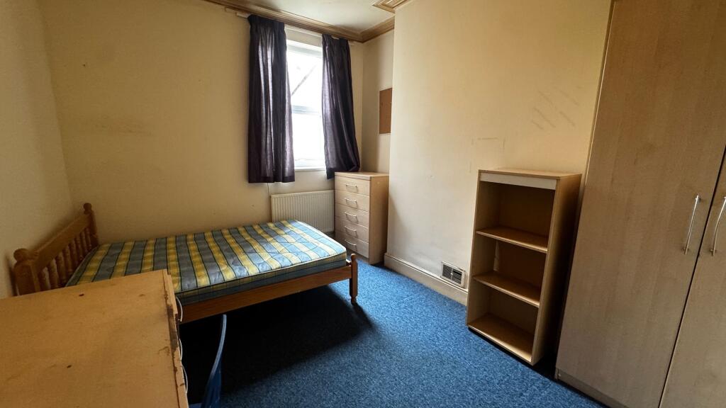 A modest single bedroom featuring a single bed,...