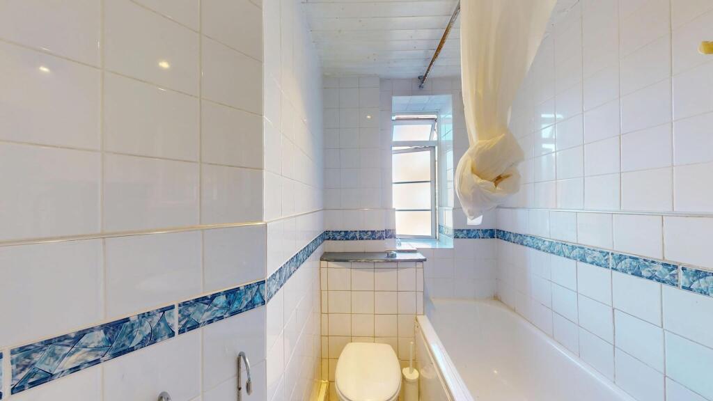 Bright and functional bathroom with white tiled...