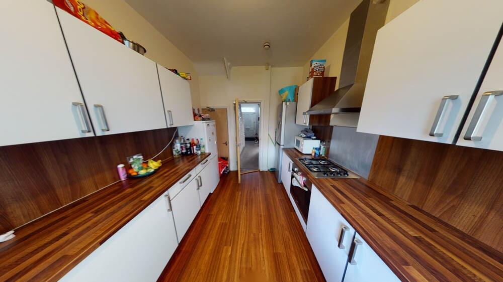 A long, modern kitchen featuring white cabinetr...