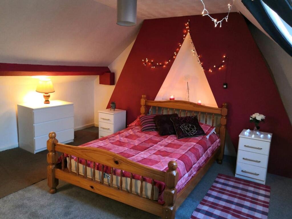 A cozy double bedroom with a wooden bed, decora...