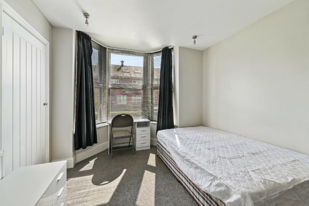 Bright and cozy bedroom featuring a large bay w...