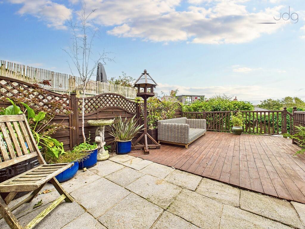 Spacious garden with a mixed of decking, artificial lawn and a pond
