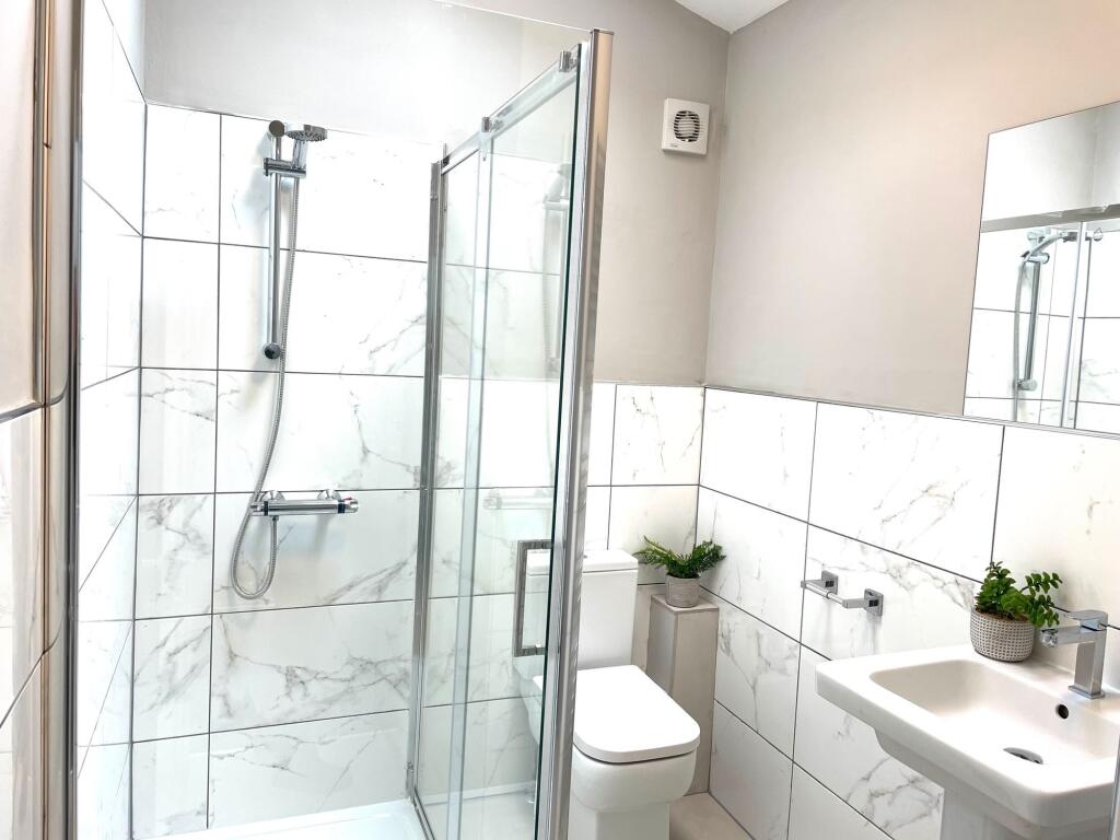Modern bathroom featuring a glass-enclosed show...