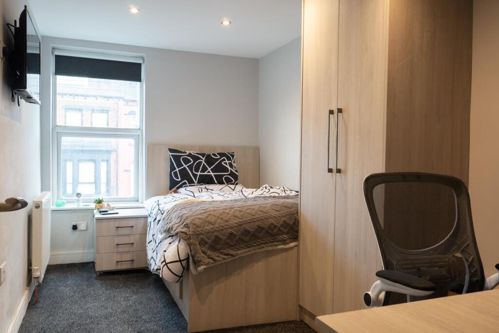 A cozy and well-lit bedroom featuring a double ...