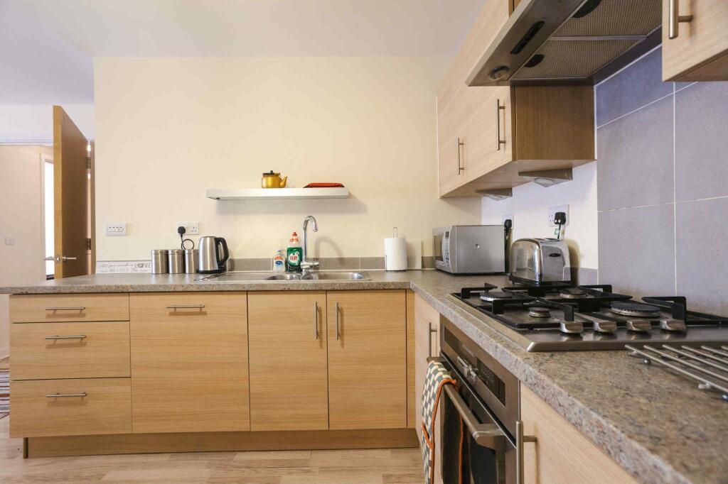 Modern kitchen with light wood cabinets, granit...