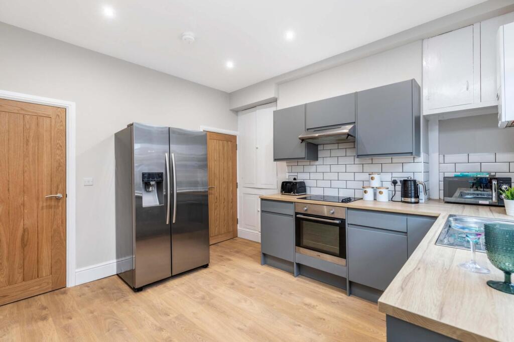 Modern open-plan kitchen with grey fitted cabin...