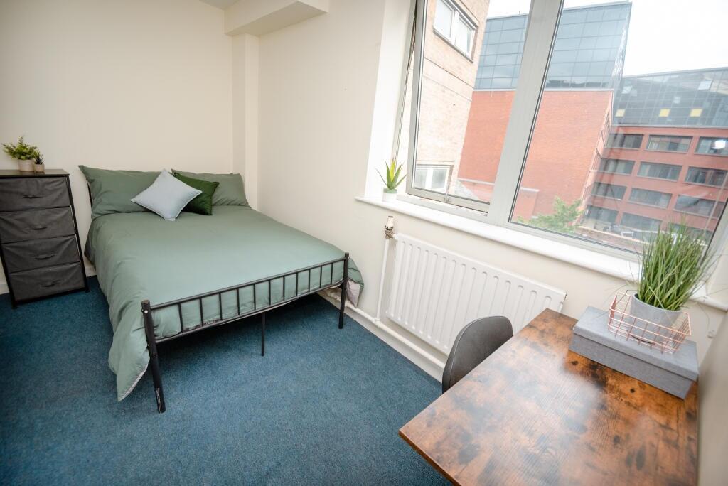 A cozy and well-lit single bedroom featuring a ...