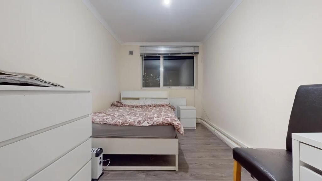 A neat and simple bedroom featuring a white bed...