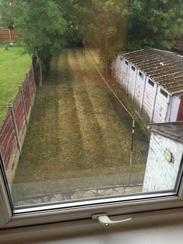 Rear garden with a long, neatly mown lawn borde...