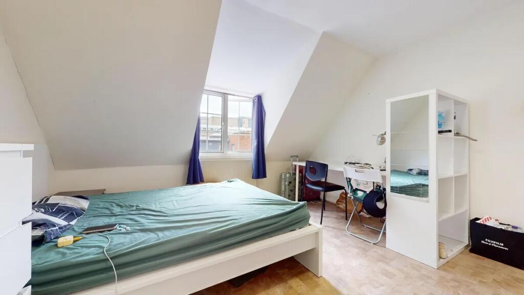 A bright double bedroom featuring a large windo...
