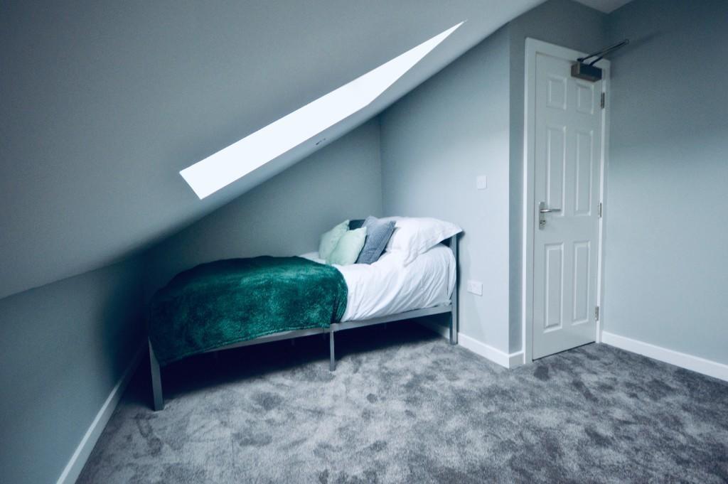 Cozy single bedroom featuring a comfortable bed...