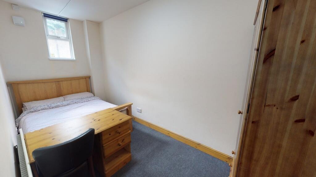 A neat and cozy single bedroom featuring a wood...