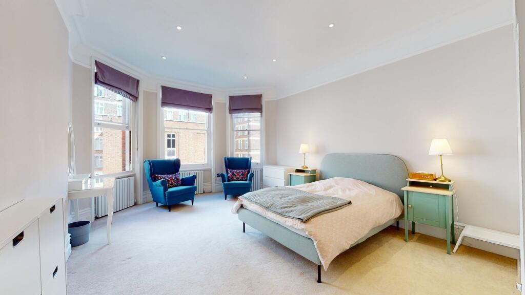 A spacious master bedroom featuring a comfortab...