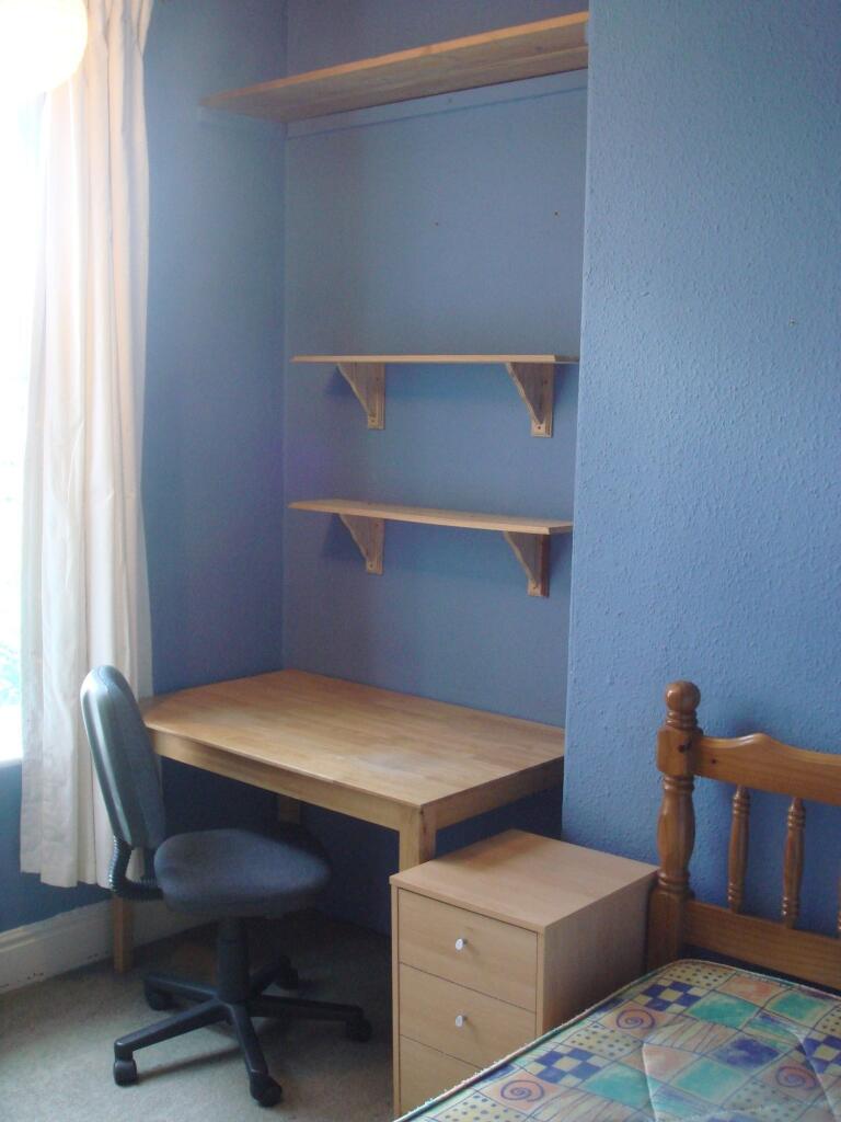 A simple, tidy bedroom featuring a wooden desk ...