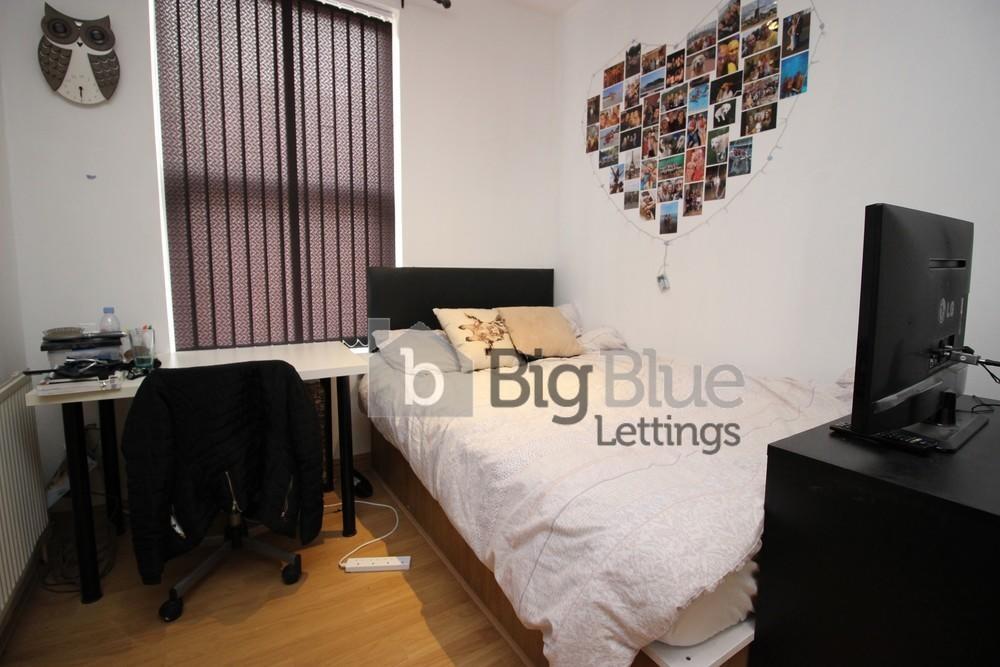 A cozy single bedroom featuring a neatly made b...